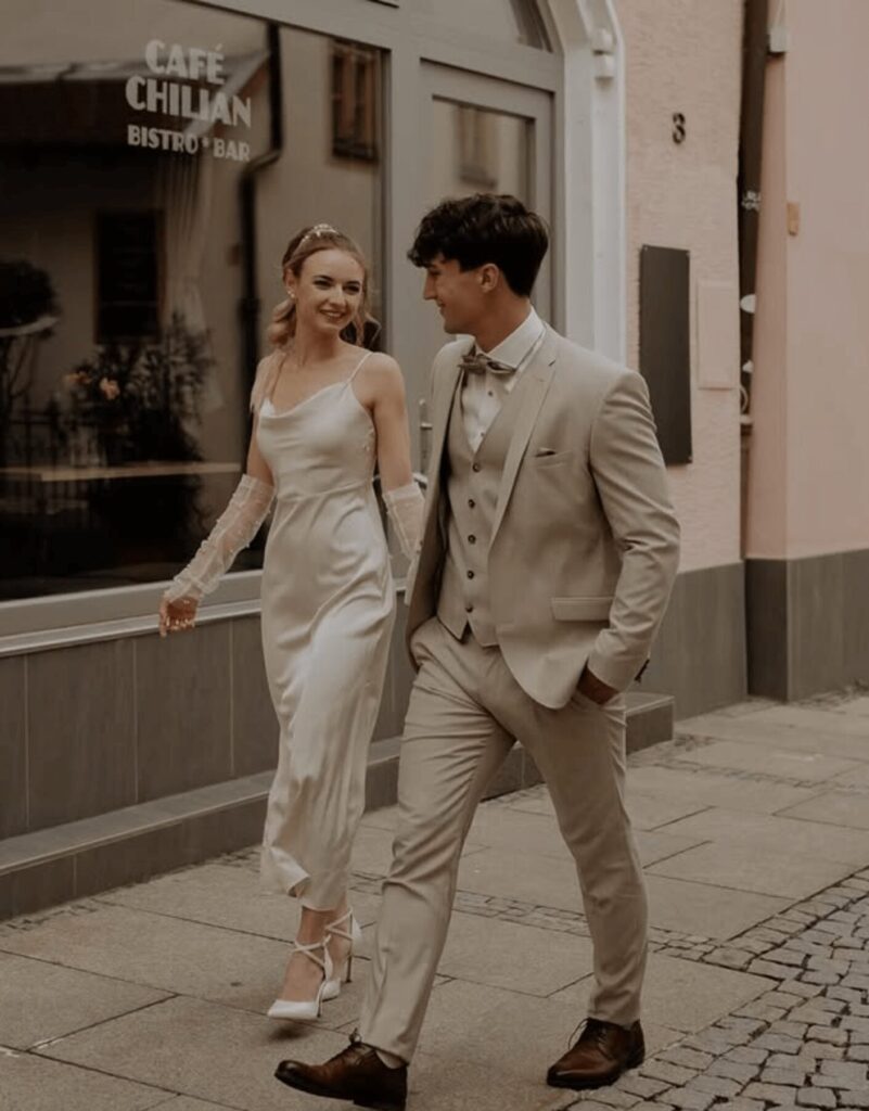 junges Brautpaar spaziert auf einem Gehsteig