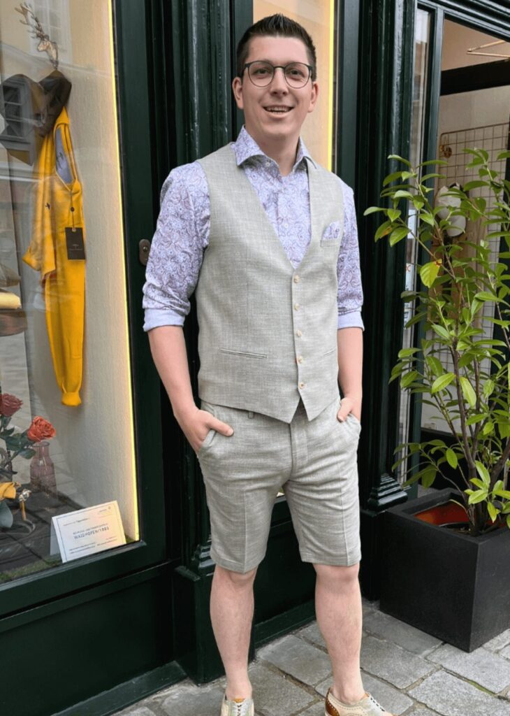 Mann probiert Anzug an, steht vor dem Geschäft Herrenmode Pöchhacker