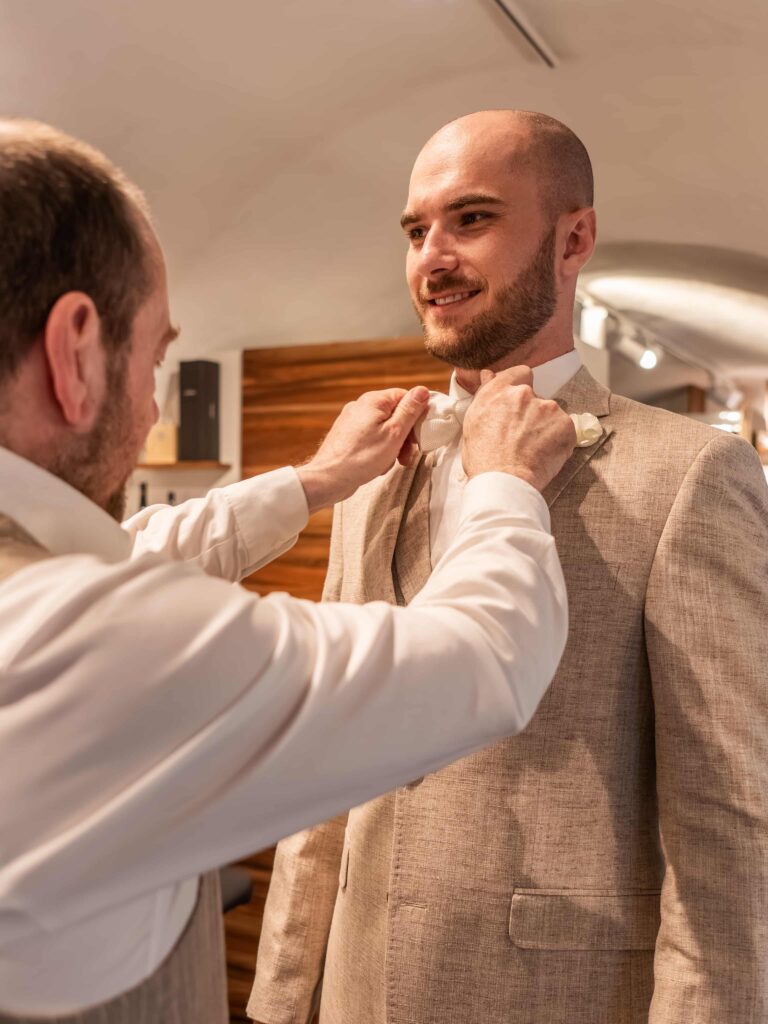 Mitarbeiter hilft Kunden bei der Anprobe einer Fliege