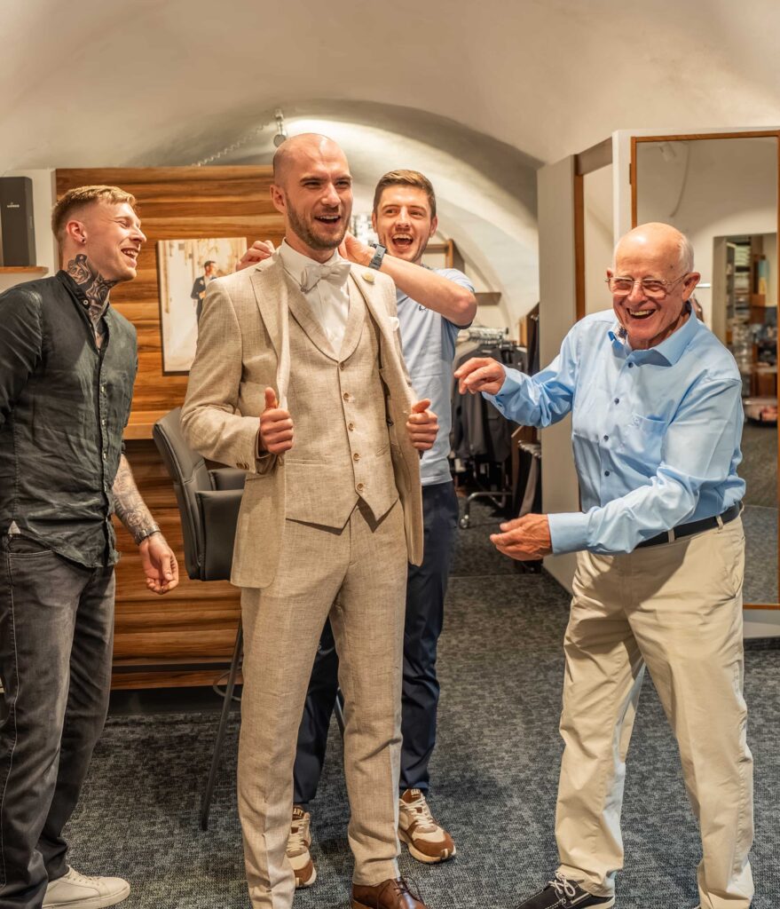 junger Mann mit seinen Freunden bei der Anzugsanprobe