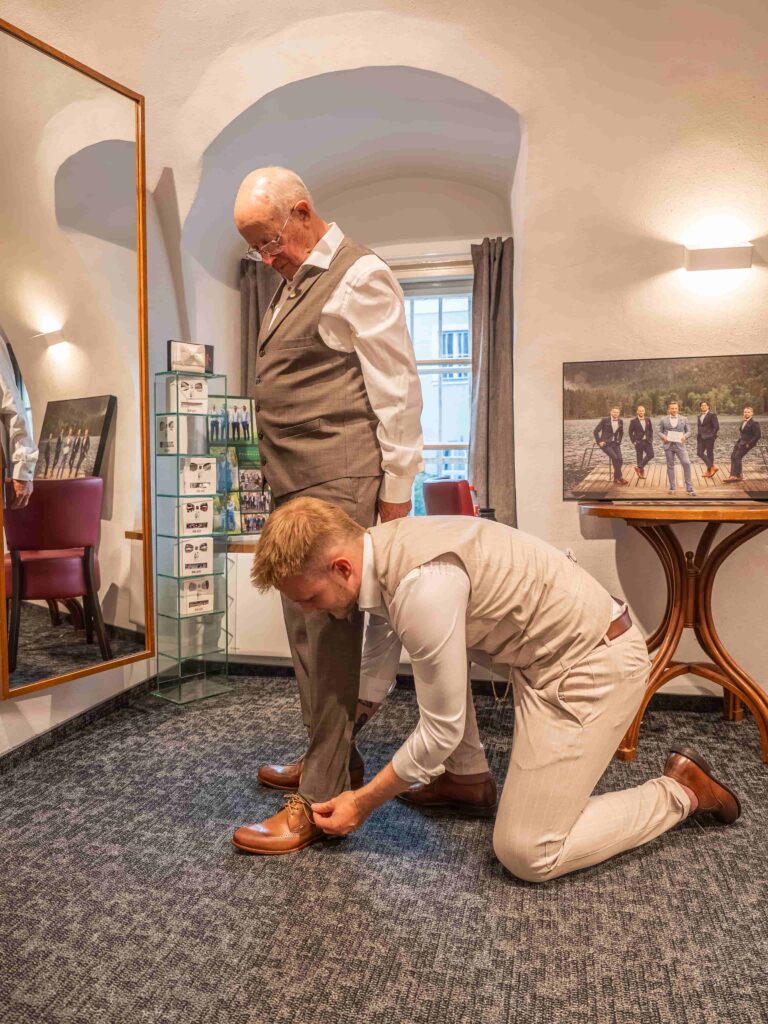junger Herr berät älterem Herren bezüglich der Hosenlänge in der Schneiderei